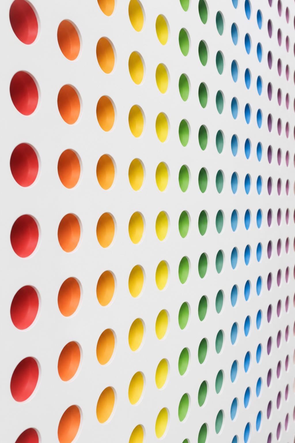 Perforated wall with rainbow colored discs — symbol of inclusion in the MICE industry